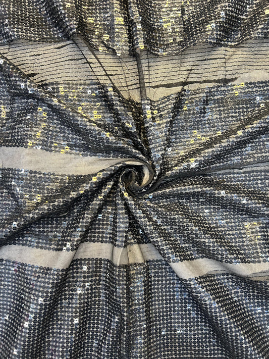 Close-up of shimmering black net textile with intricate gold sequin work, ideal for elegant sarees, anarkalis, and Indo-Western outfits.