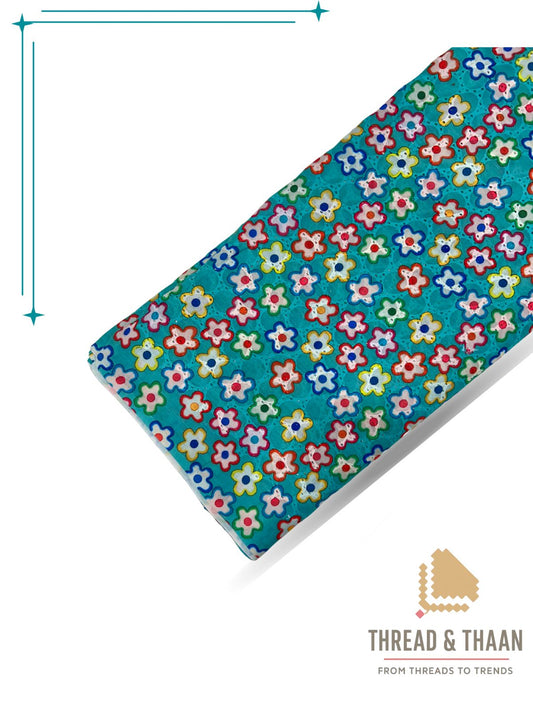Vibrant turquoise pure cotton Hakoba fabric with multicolor floral print and delicate cutwork embroidery, perfect for stylish summer dresses and kurtas.