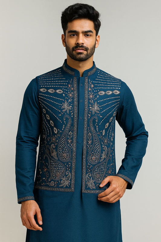 Elegant men's Teal Blue Kurta Koti Pajama Set for weddings. A model wears the traditional Indian outfit featuring a richly embroidered koti (waistcoat) with dense silver-grey paisley and floral threadwork. This premium ethnic wear is ideal for grooms, wedding guests, receptions, or formal festivals.