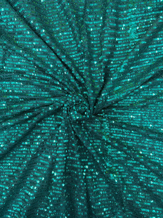Close-up of stretchy emerald sequin net fabric, offering comfort and sparkle for custom dance costumes and designer apparel.