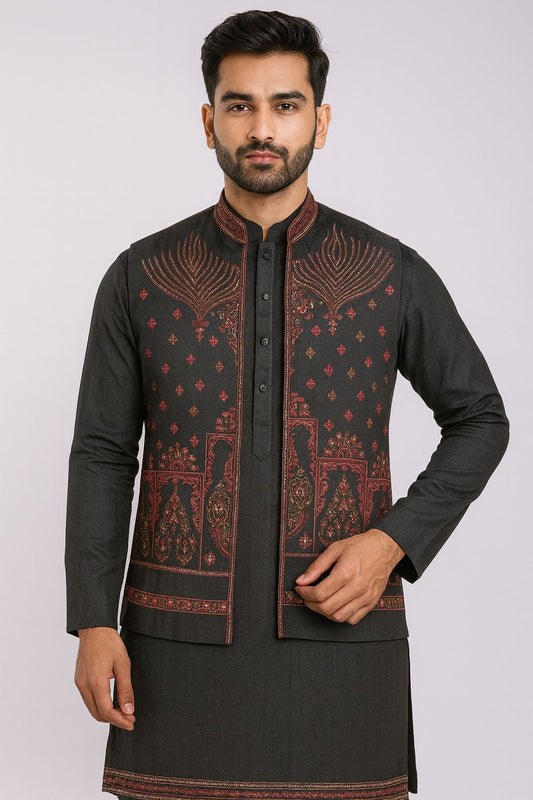 Stylish men's black Kurta Pajama Set layered with an embroidered waistcoat (Koti). The Koti features intricate red and gold threadwork in a geometric or floral pattern. This dark ethnic outfit is perfect for Diwali, Sangeet, or winter wedding functions.